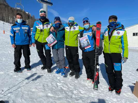 Presidënt y alenadus dl Ski Team Alta Badia cun i patruns dl lift de Gardenacia. Ai tëgn tla man le foliet »Ski Team Alta Badia Magazine«, che ai á dé fora chësc invern por se presenté, por porté dant i atlec, i proiec y les ativités che ai mët da jí. 
