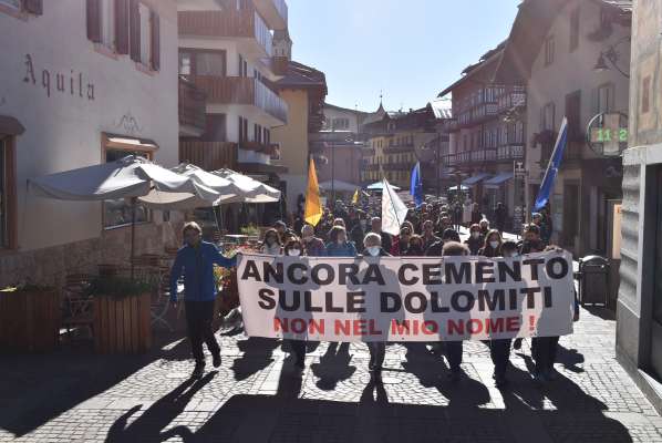 Ignante par piaza, dapò su par ra pista da bob de Ronco: ra manifestazion de i anbientalistes contra i laore masa grei su ra Dolomites, par ra Olimpiades d’inverno 2026.
