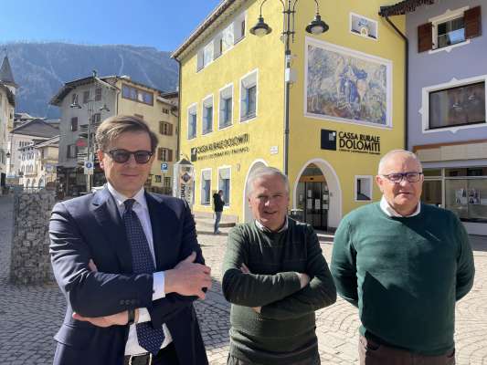 L diretor Ruggero Lucin, l president Carlo Vadagnini e l vizepresident Maurizio Bonelli dedant a la senta zentrèla de la Cassa Rurala Dolomiti a Moena.
