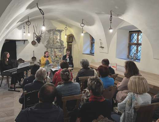 Pra la sëira leterera tl Ciastel de Gherdëina. Da m.c.: Linda Rungger, che à acumpanià cun tlavier y usc, Nadia Rungger, autëura, y Bruno Maruca, muderadëur.
