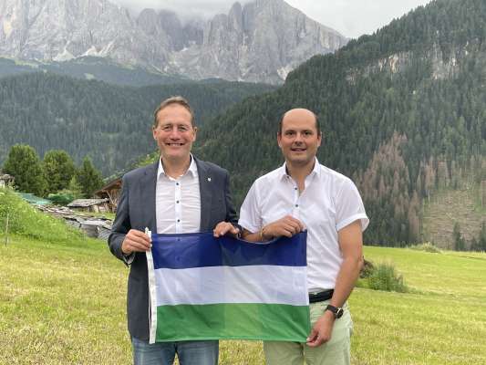 L assessëur provinziel y cunselier regiunel Massimo Messone cun l assessëur de Urtijëi Stefan Kasslatter. Cun ëi: la bandiera ladina.
