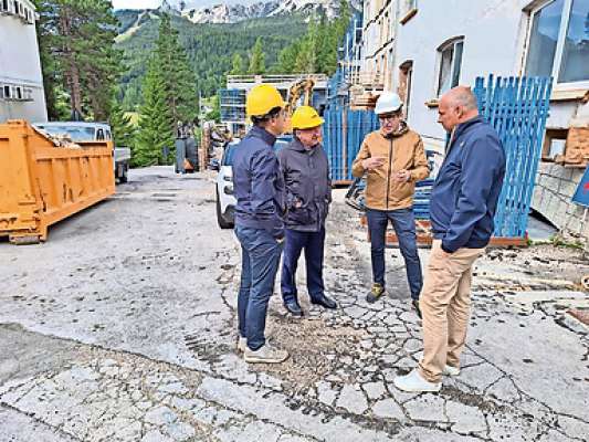 Gianluca Lorenzi Chenopo capocomun de Anpezo, el loudaduó Stefano Ghezze Ghezo e Giuseppe Dal Ben comisario de ra Ulss 1 de Belun i varda el cantier de ‘l ospedal Codivilla.
