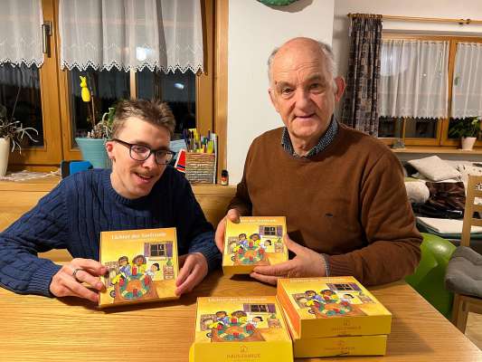 Elias Frontull y so berba siur Tone Fiung mostra cun ligrëza le calënder d’Advënt nü.
