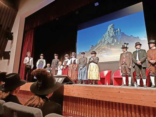 Ra tradizios de i Ladis de ra Dolomites e cheres de i cazadore, aduna sul palco de ‘l Alexander Girardi Hall in Anpezo, par ra foula granda de ra Uncza.

