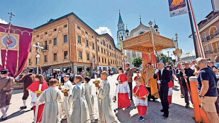 Ra portiscion del Corpus Domini con el pioan che el porta el Santisimo par ra strade e piazes del paes.
