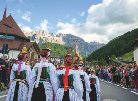 La mutans cun la gherlanda spiza ntan la defileda de »Gherdëina cun la troht« te Sëlva.   (Foto Lia dl Turism Sëlva)
