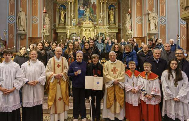 Gran sudesfazion per la Palestrina d'or: ministronc y ministrontes cun (da m.c.) Sn. digan Ivo Costanzi, la sëurastanta dl Cor y dla Urchestra de Dlieja Margit Peristi, la dirighënta Felicitas Schweizer y pater Urban sëurastant dl VKM. 
