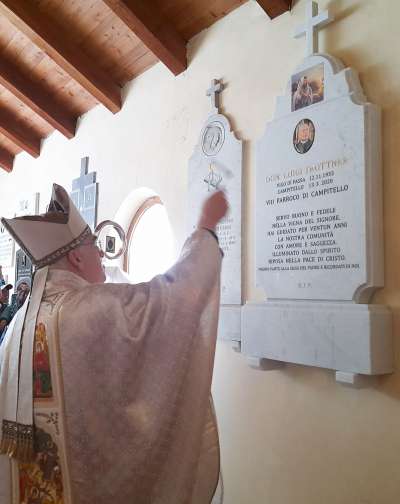 L Piscop Lauro benedesc la plota de recordanza sot teac de gejia.
